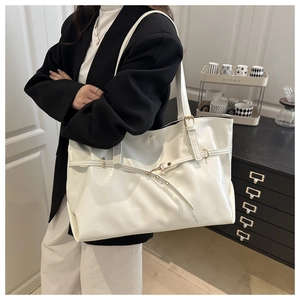 Detail of white glossy tote bag showing large capacity and side gold buckle hardware