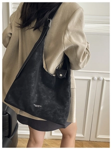 Detail of a large black vintage tote bag with white lettering and adjustable shoulder strap