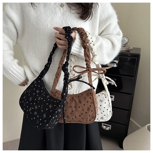 Detail view of corduroy hobo bags with heart bow patterns in black, brown and cream