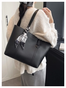 Modern black PU leather tote bag with printed silk scarf detail worn by a model