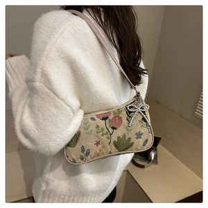 Close-up of vintage floral jacquard crescent bag with a diamond bow charm and leather strap