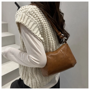 Detailed shot of retro brown leather shoulder bag with decorative strap knot and silver ring