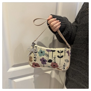 Detail of embroidered floral tote bag with pearl bow charm held against white door