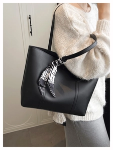 Detail of black PU leather tote bag featuring a decorative printed silk scarf on the handle