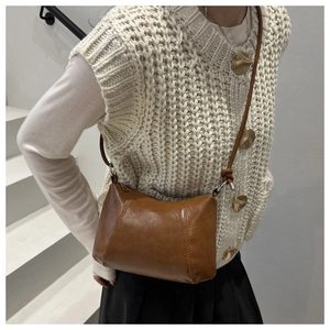 Caramel brown leather crossbody pillow bag shown on a model in a lifestyle setting