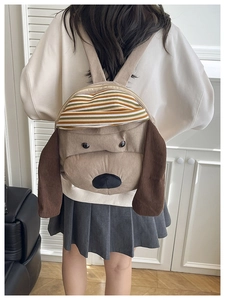Close-up of khaki corduroy puppy backpack featuring 3D ears and striped hat detail