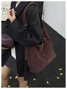 Outdoor shot of large burgundy faux suede tote bag and matching clutch pouch with logo detail