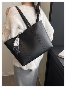 Detail of matte black PU tote bag with a decorative black and white polka dot silk scarf