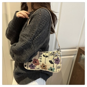 Detail of floral tapestry crescent bag with sparkling bow accent on a female shoulder