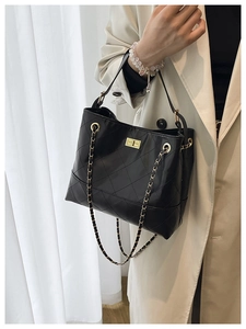 Detail showing black quilted texture and golden chain strap on large tote bag