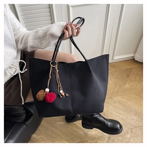 Detail of black vintage tote bag featuring a colorful tassel charm with plush pom-poms