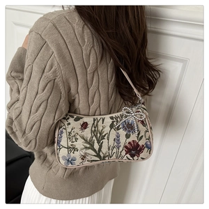 Detail of floral tapestry underarm bag with silver bow charm and leather strap