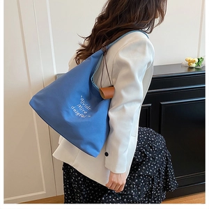 Blue canvas tote bag shown as a shoulder bag on a model for a stylish daily commute look