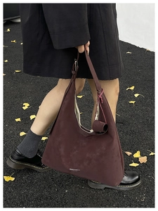 Detail view of burgundy matte leather Hobo bag featuring a side logo and matching charm