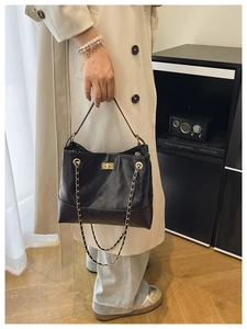 Detail of black quilted bucket bag featuring a gold twist lock and elegant chain strap