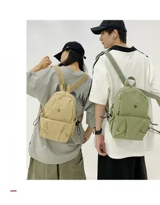 Detail of lightweight nylon backpacks in beige and green featuring front zipper pockets