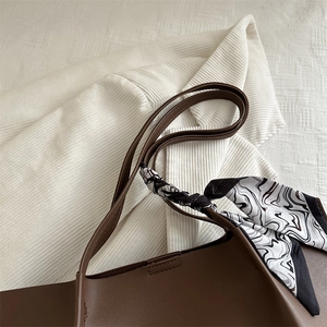 Dark brown tote bag with marble pattern scarf on white textured fabric background