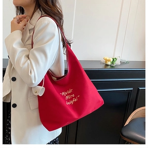 Close-up of red canvas tote bag with white letter embroidery and a mini round pouch