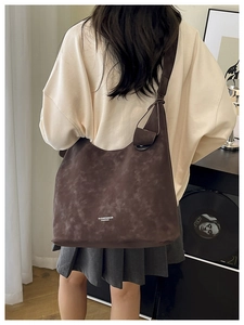 Model wearing dark brown hobo bag with knotted strap detail and suede finish
