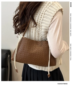 Detailed weave pattern on brown shoulder bag with decorative side drawstrings on model
