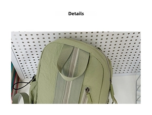 Detail view of the light green nylon backpack with top zipper closure and webbing handle