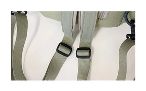 Detail of light green backpack showing nylon straps and silver metal zipper puller