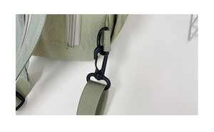 Detailed view of silver metal zipper and black plastic buckle on light green nylon backpack