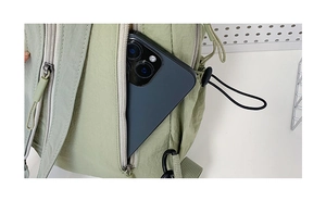 Detail view of a side zipper pocket on a green nylon bag holding a smartphone