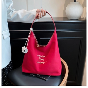 Close-up of a red canvas tote bag with white lettering on a wooden chair for daily use