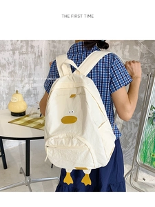 Detail of cute duck backpack in beige nylon with 3D yellow duck beak and feet details