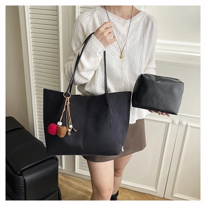 Detail of black suede tote bag and matching pouch with colorful pompom charm