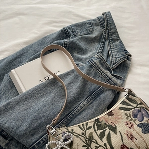 Floral canvas hobo bag with pearl heart pendant on casual denim jacket backdrop