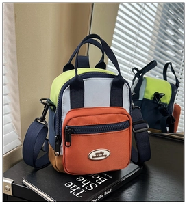 Detailed shot of multi-color nylon crossbody bag on a black wooden desk with natural lighting