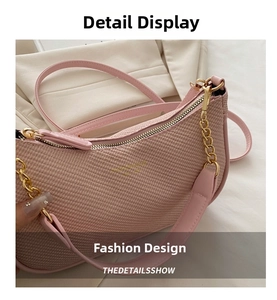 Detail of light pink crescent underarm bag with woven texture and gold chain strap