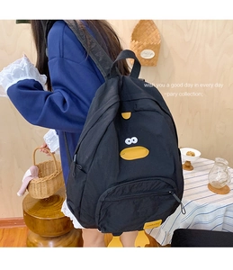 Detail view of a black cartoon duck backpack with 3D beak and webbed feet on a model