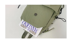 Close-up of light green nylon bag showing metal magnetic buckle and book storage detail