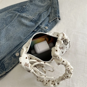 White corduroy crescent shoulder bag with bow prints and pleated handle detail