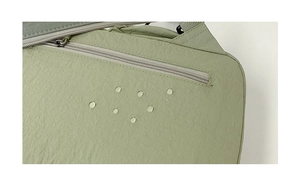 Close-up of water-resistant green nylon fabric with droplets on a multifunctional backpack