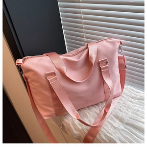 Detailed shot of pink waterproof nylon travel bag with crossbody strap and metal hardware