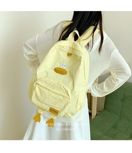 Detail of a light yellow cartoon duck backpack with durable nylon fabric and leather label