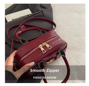 Detail of smooth gold-tone dual zippers on vintage burgundy leather pillow bag