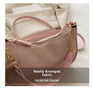 Detail of pink woven underarm bag featuring golden chain and premium metallic zipper