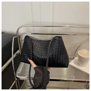 Detail of premium black hand-woven leather texture and Intrecciato craftsmanship on shoulder bag