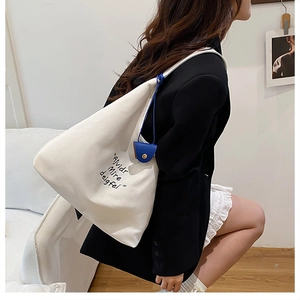 Close-up of white canvas tote bag with black typography and a blue button charm accessory