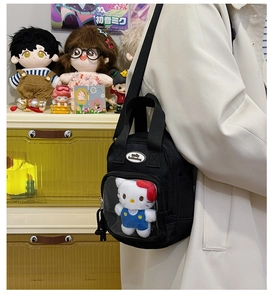 Detail of black canvas crossbody bag with clear PVC window and Hello Kitty plush toy inside