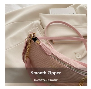 Detail of pink woven underarm bag with gold metal zipper on white blazer background