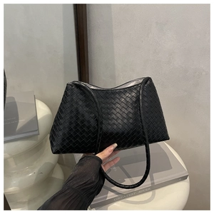 Close-up of black woven leather texture on chic underarm bag with minimalist shoulder strap