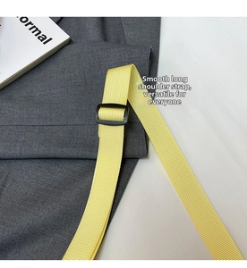 Macro detail of adjustable yellow woven shoulder strap with black plastic buckle closure