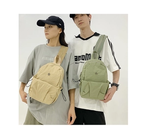 Detail view of nylon crossbody bags in beige and light green with drawstring features