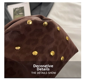 Dettaglio in pelle leopardata marrone con borchie dorate e lavorazione a pieghe